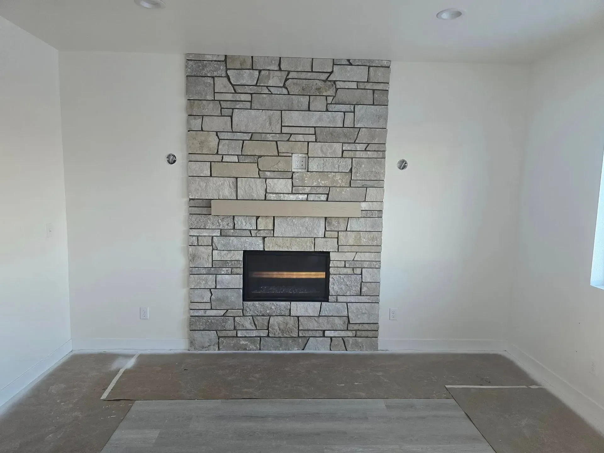 Stone fireplace in a room with light-colored walls, with a hearth and a dark firebox.