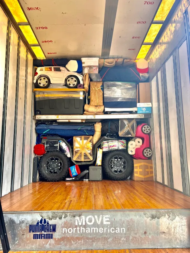 Packed moving truck with furniture, boxes, and a toy car secured inside.