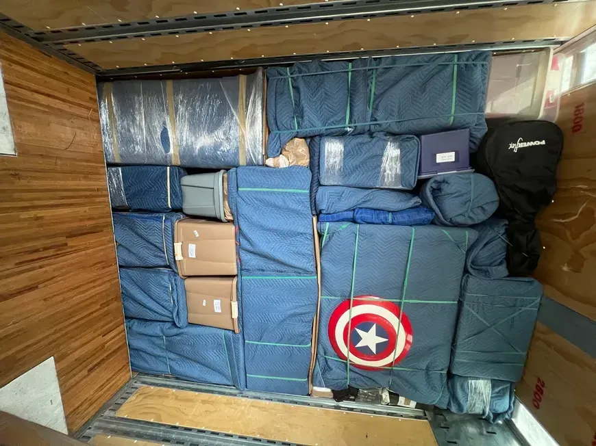 Packed cargo area filled with blue-wrapped boxes, bags, and a Captain America shield emblem