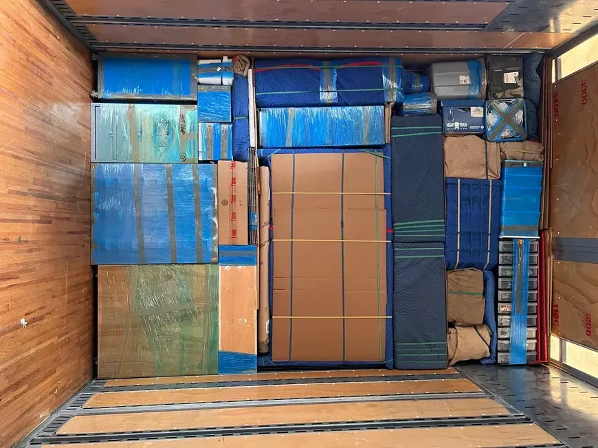 Stacked cardboard boxes and blue-wrapped cargo inside a shipping container