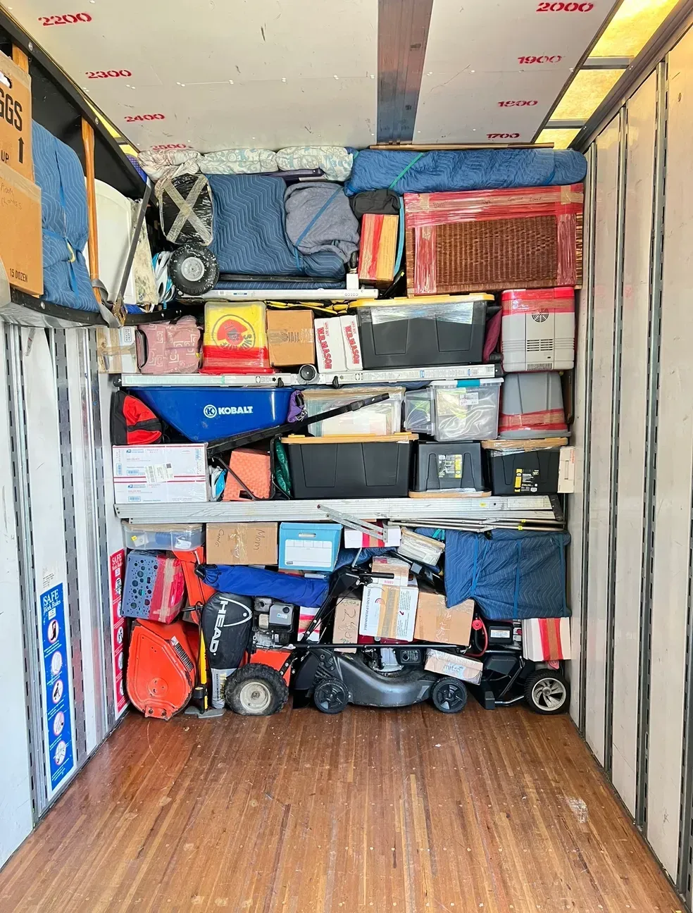 Packed moving truck with stacked boxes, bags, and household items filling the cargo area.