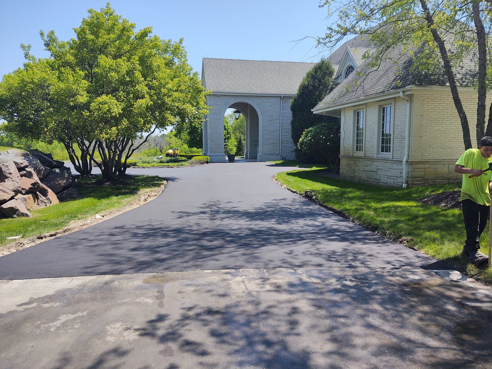 A man is standing on the side of a road in front of a house.