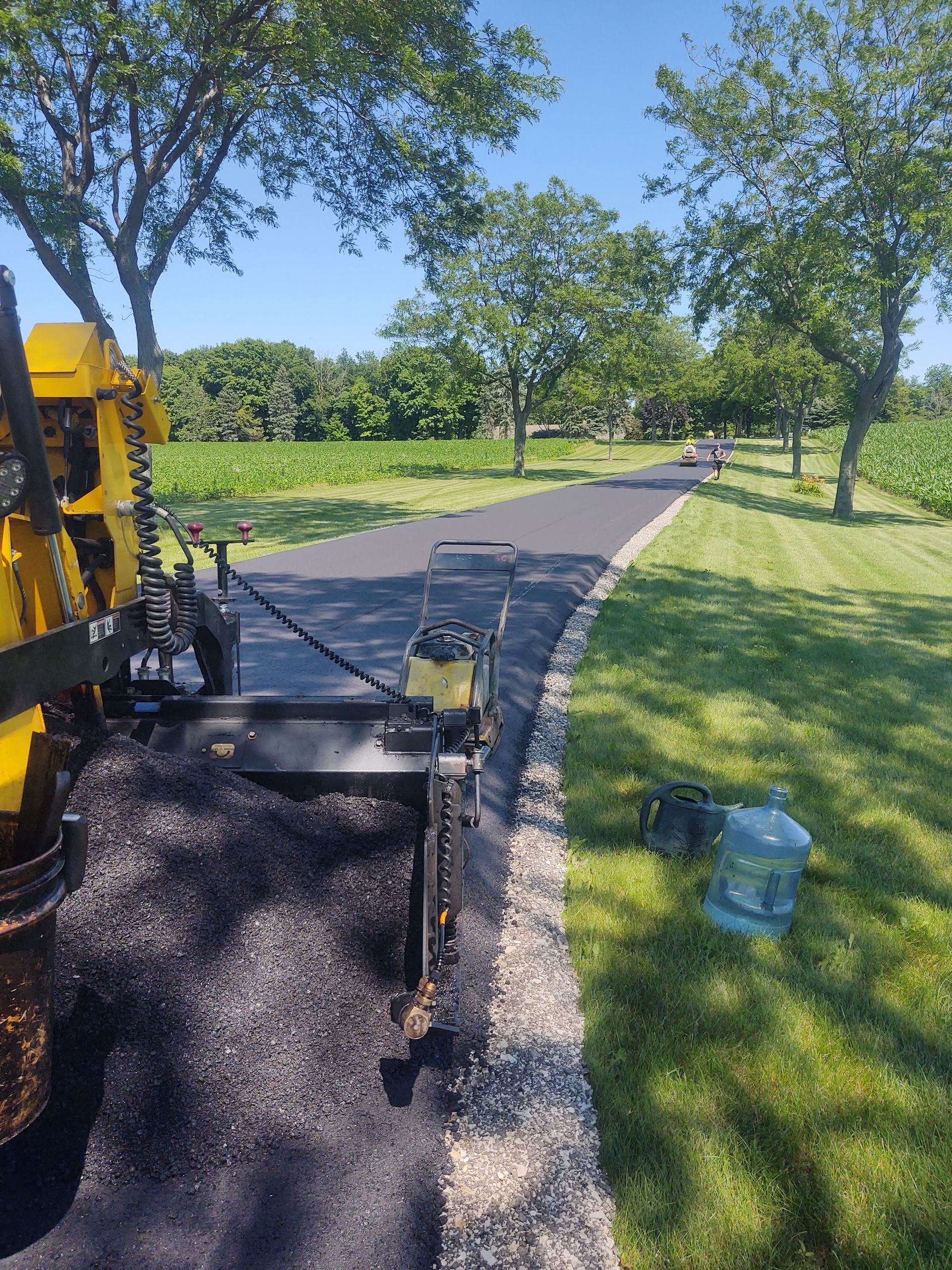 A machine is laying asphalt on the side of a road.