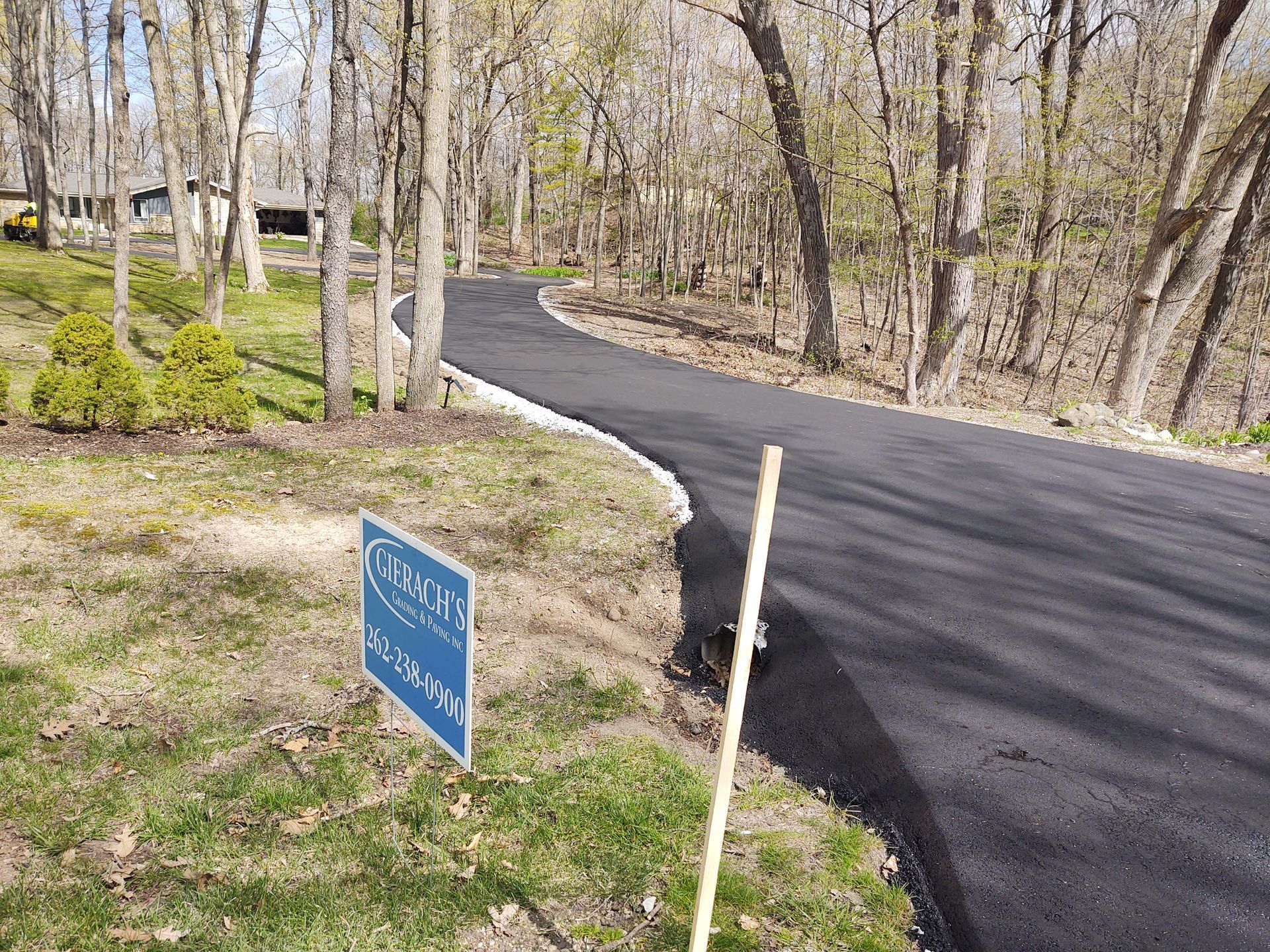 A road with a sign on the side of it goes through a forest.