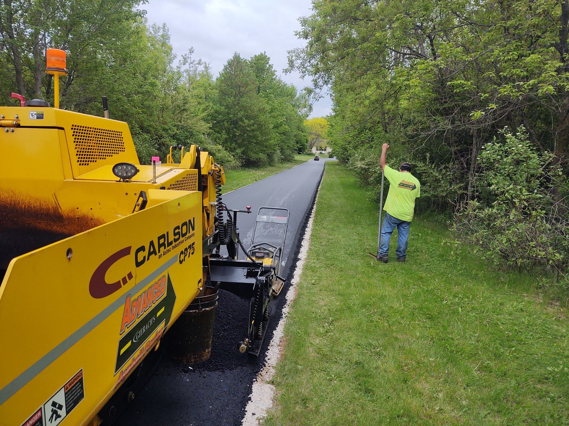 A man standing next to a carley asphalt paving machine.