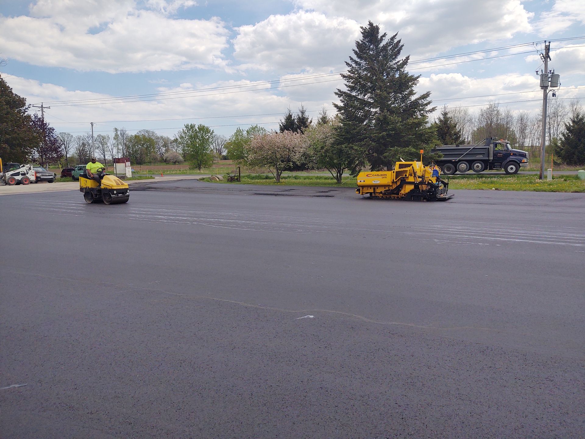 A parking lot is being paved with a truck in the background.