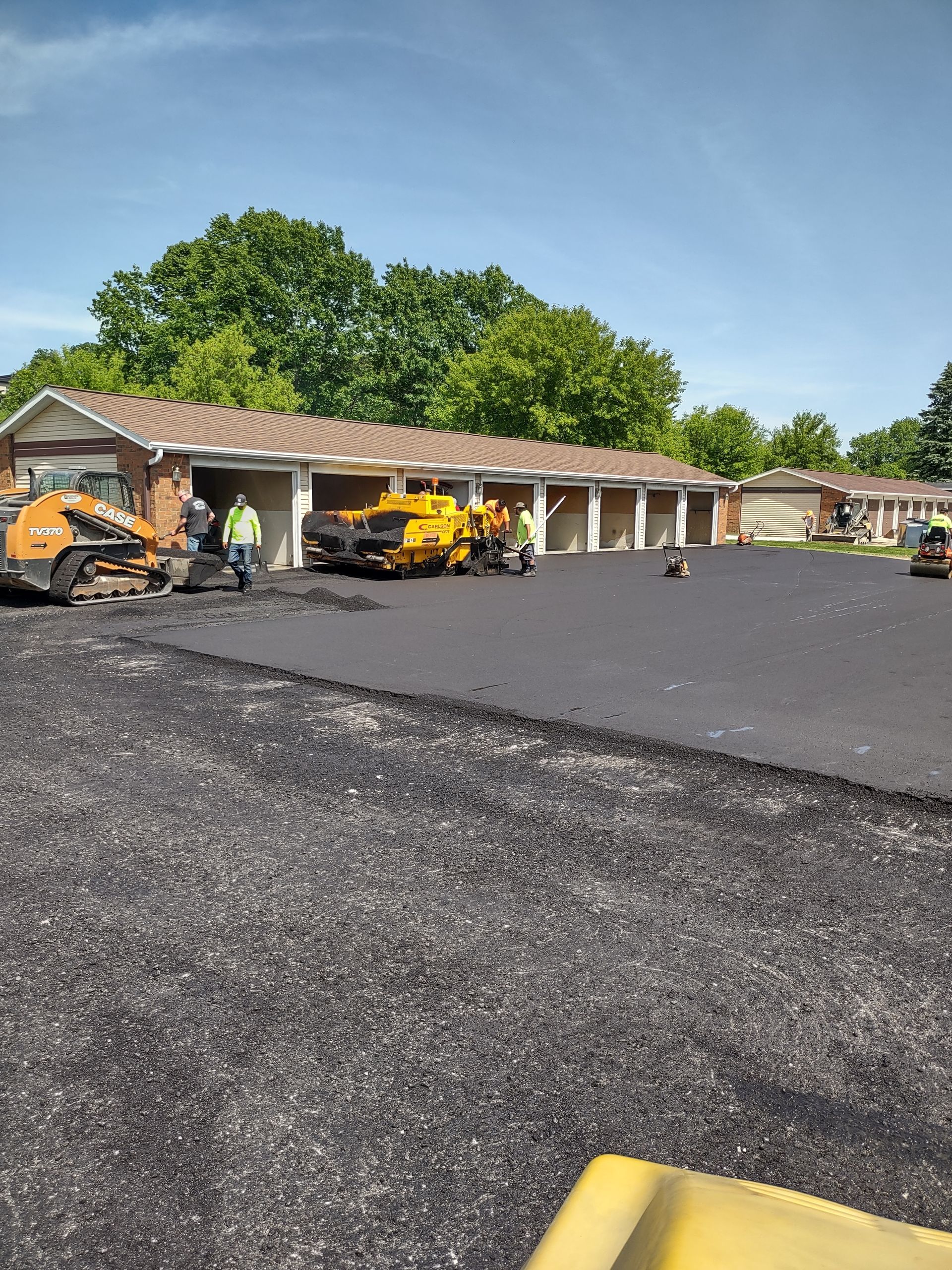 A parking lot is being paved in front of a building.