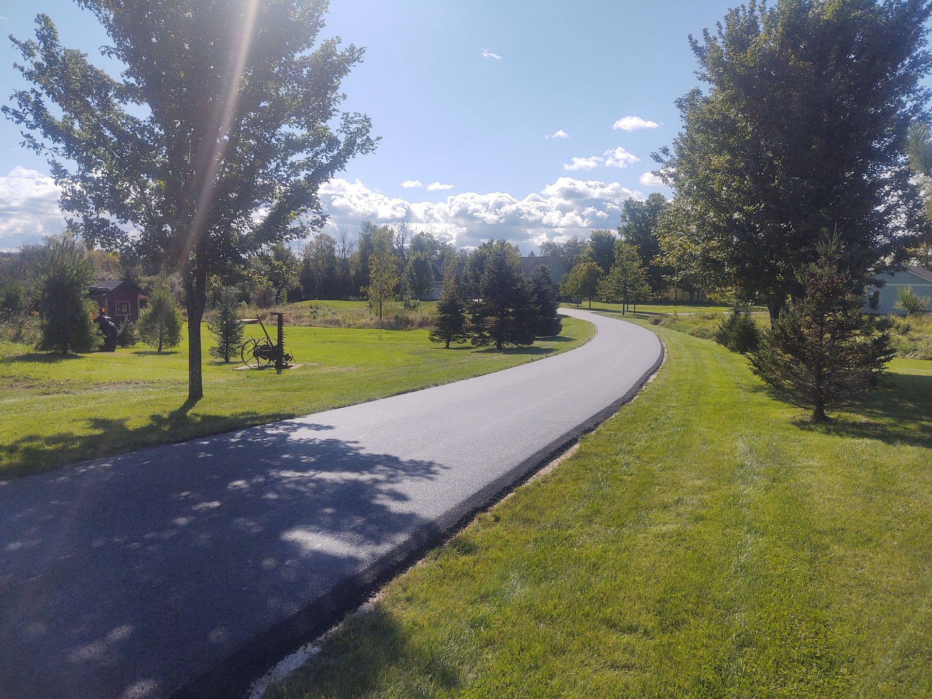 A path that is surrounded by grass and trees on a sunny day.