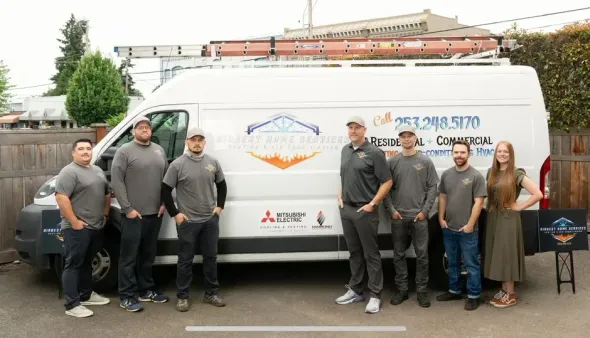 Team of people in front of a white van with company logo. Green backdrop, sunny day.