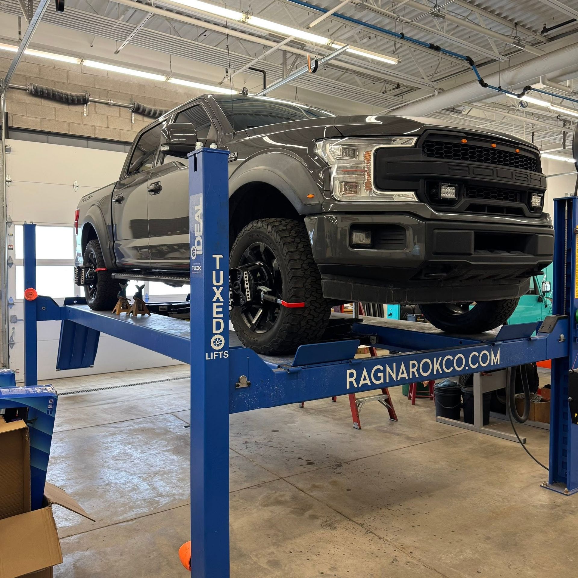 Gray pickup truck on a blue lift in an auto shop