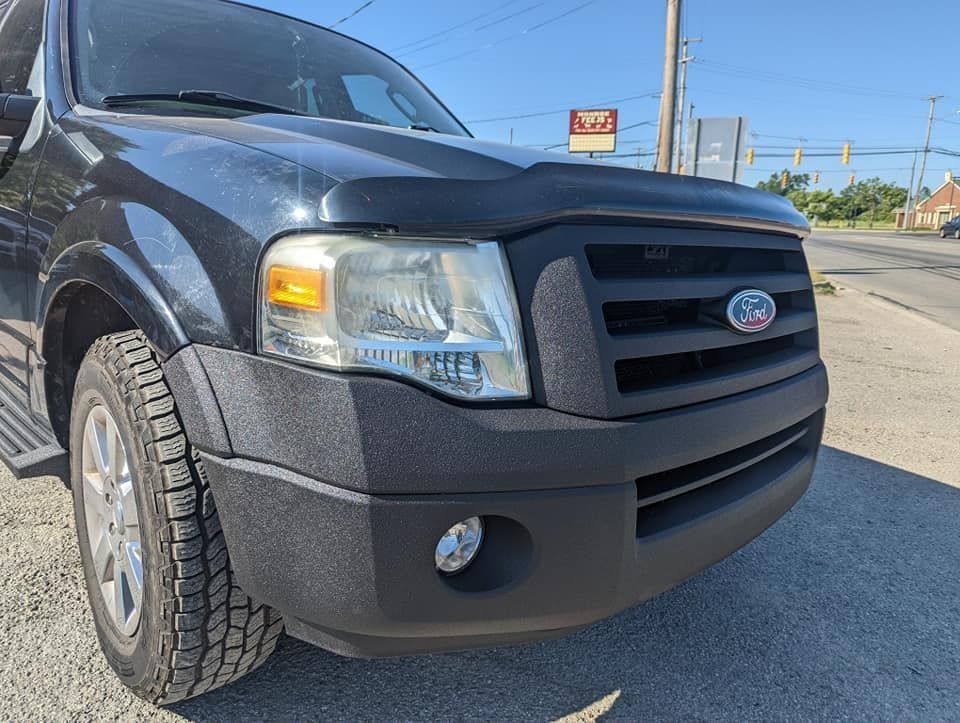 Black Ford SUV parked on a roadside under a clear blue sky