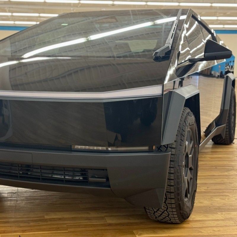 Black Tesla Cybertruck in a showroom, front-left view on a wooden floor