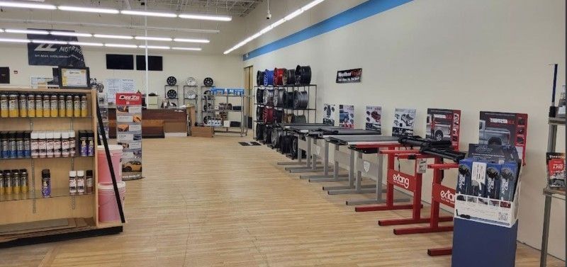Inside a bright store aisle with shelves on the left and boxed items on display on the right