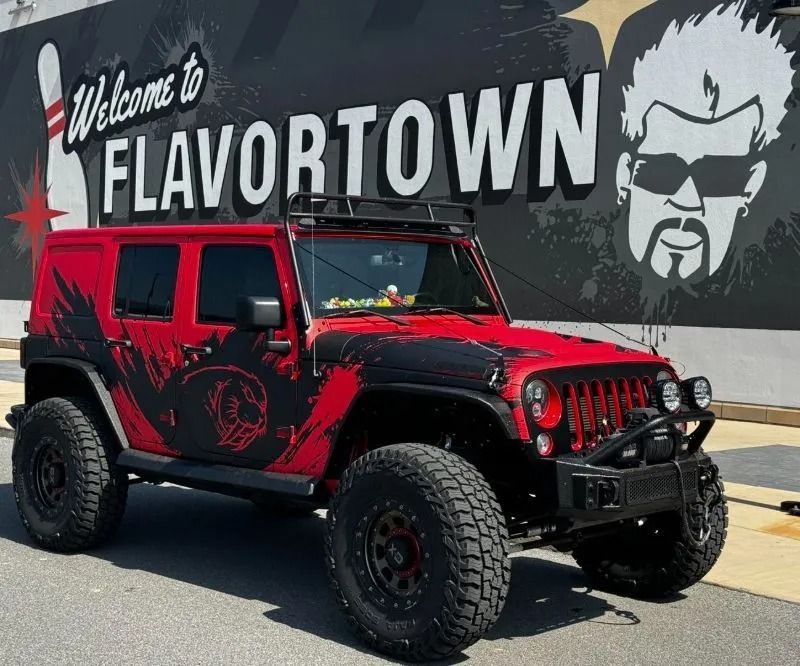 Red off-road Jeep in front of a “Welcome to Flavortown” mural with Guy Fieri’s face.