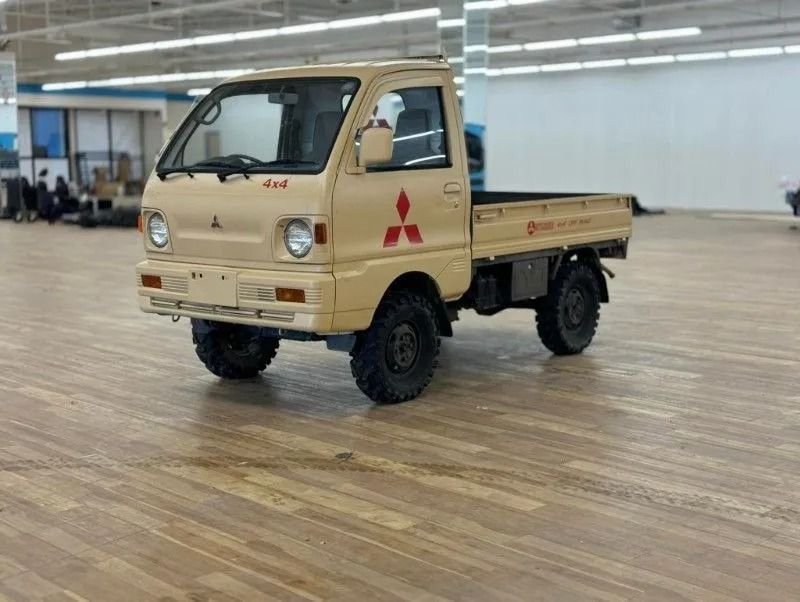 Beige mini flatbed truck displayed indoors on a polished wooden floor