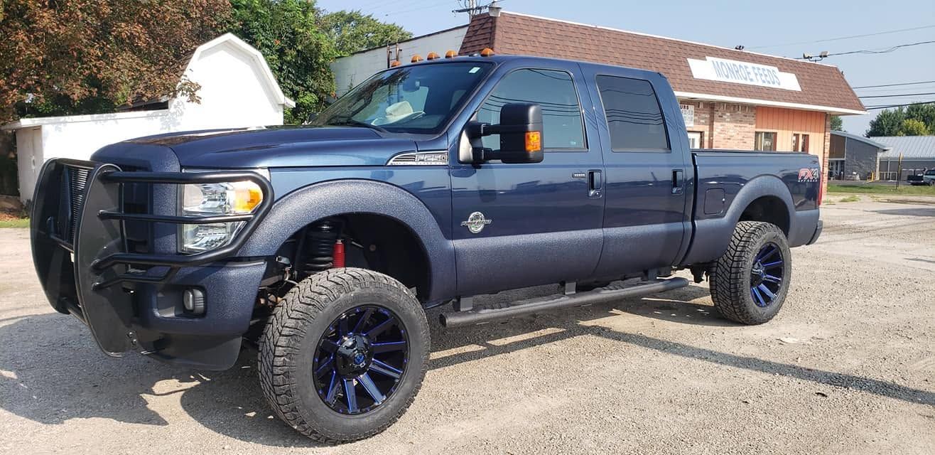 Dark blue lifted pickup truck parked outdoors in front of a building