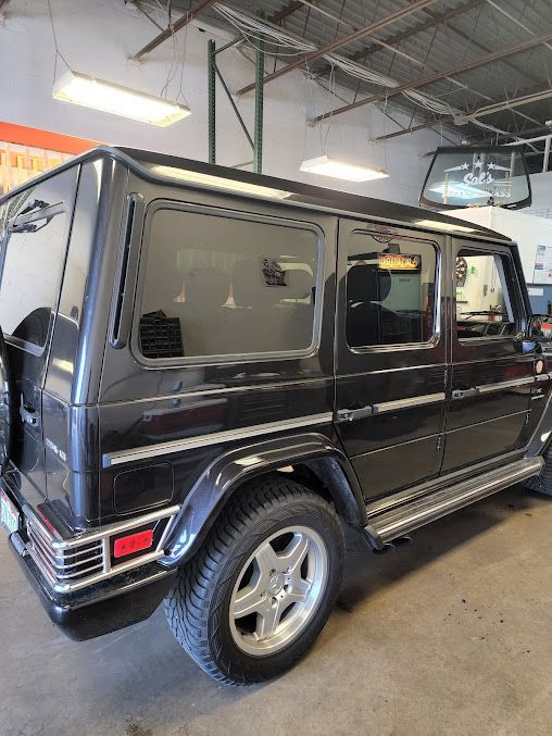 A black mercedes benz g class is parked in a garage.