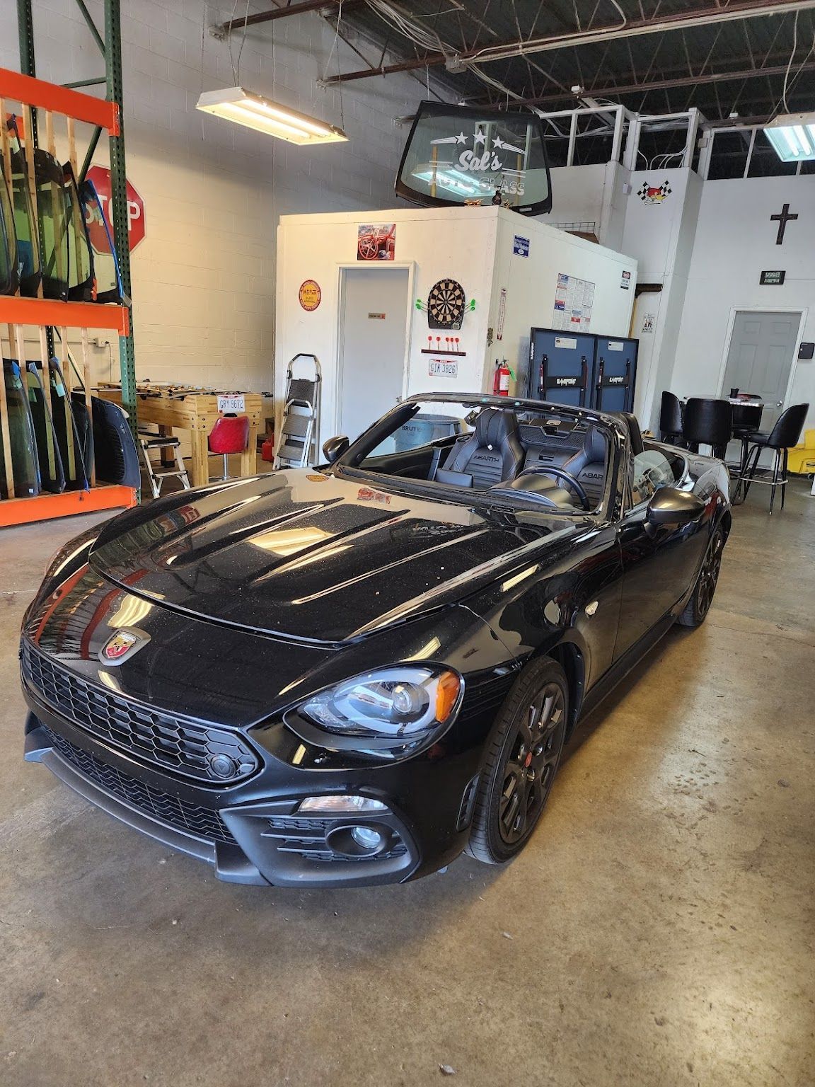 A black convertible car is parked in a garage.