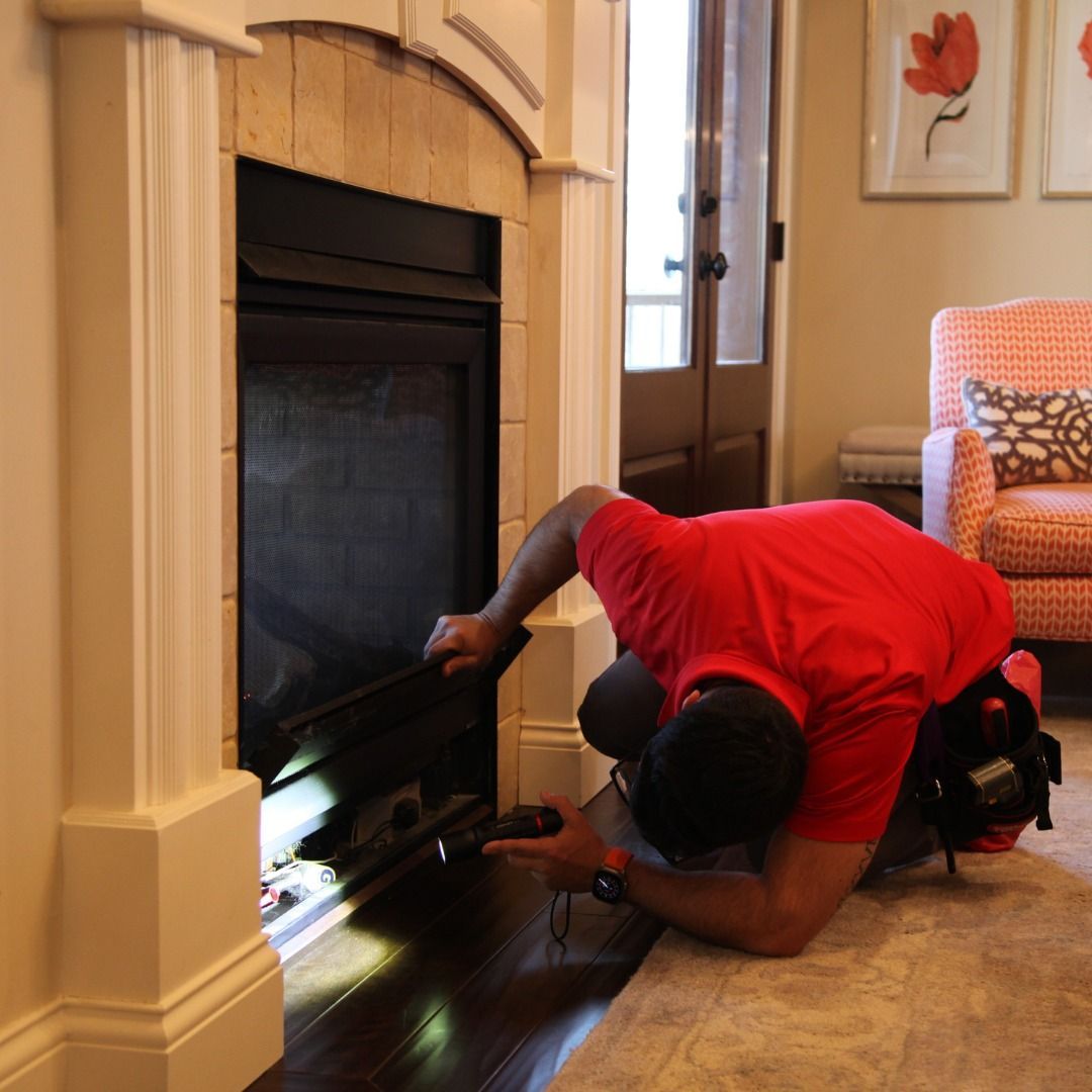 Man inspecting a fireplace with a flashlight; setting is a living room.