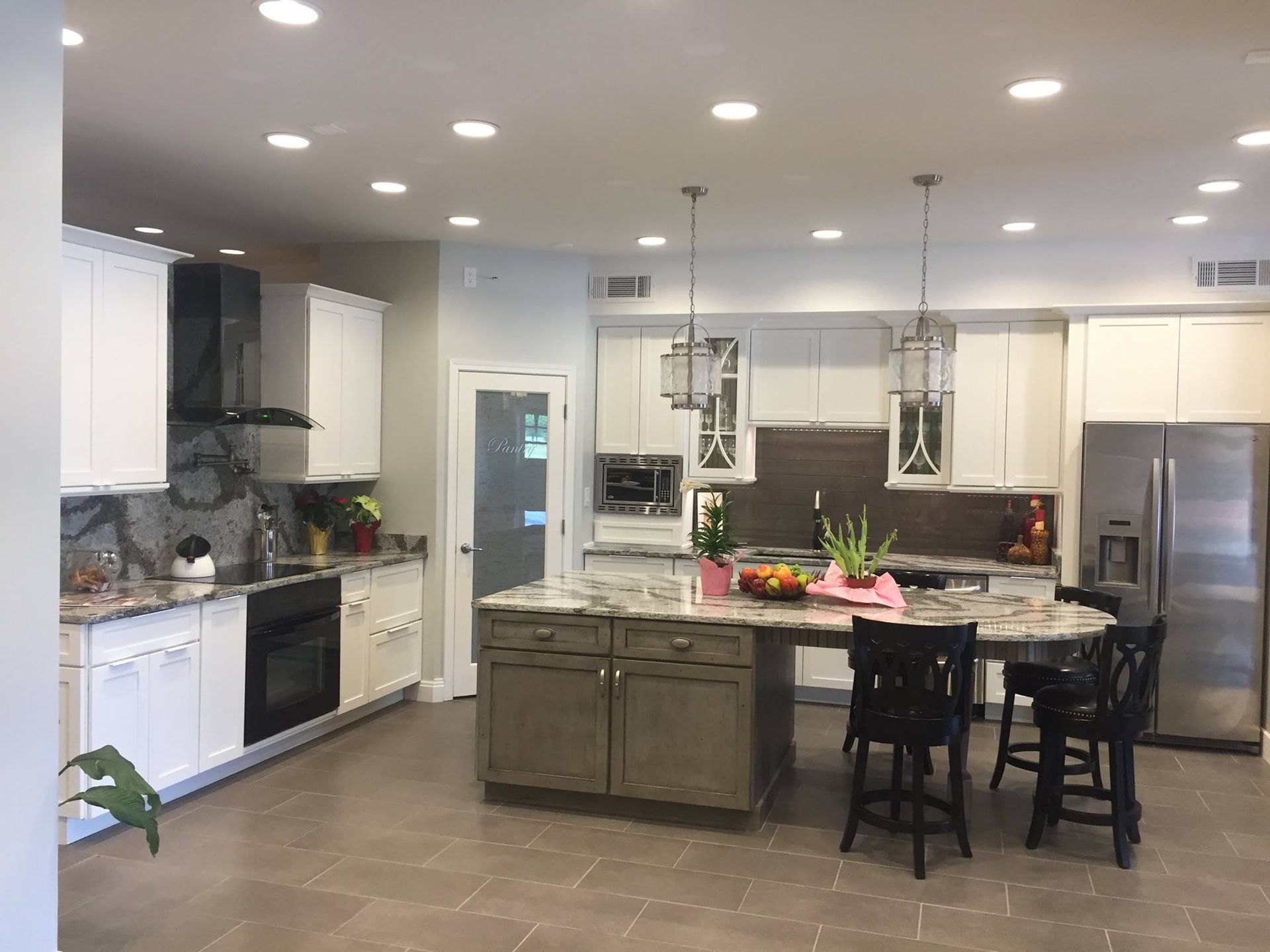 Modern kitchen with white cabinets, gray island, and stainless steel appliances.
