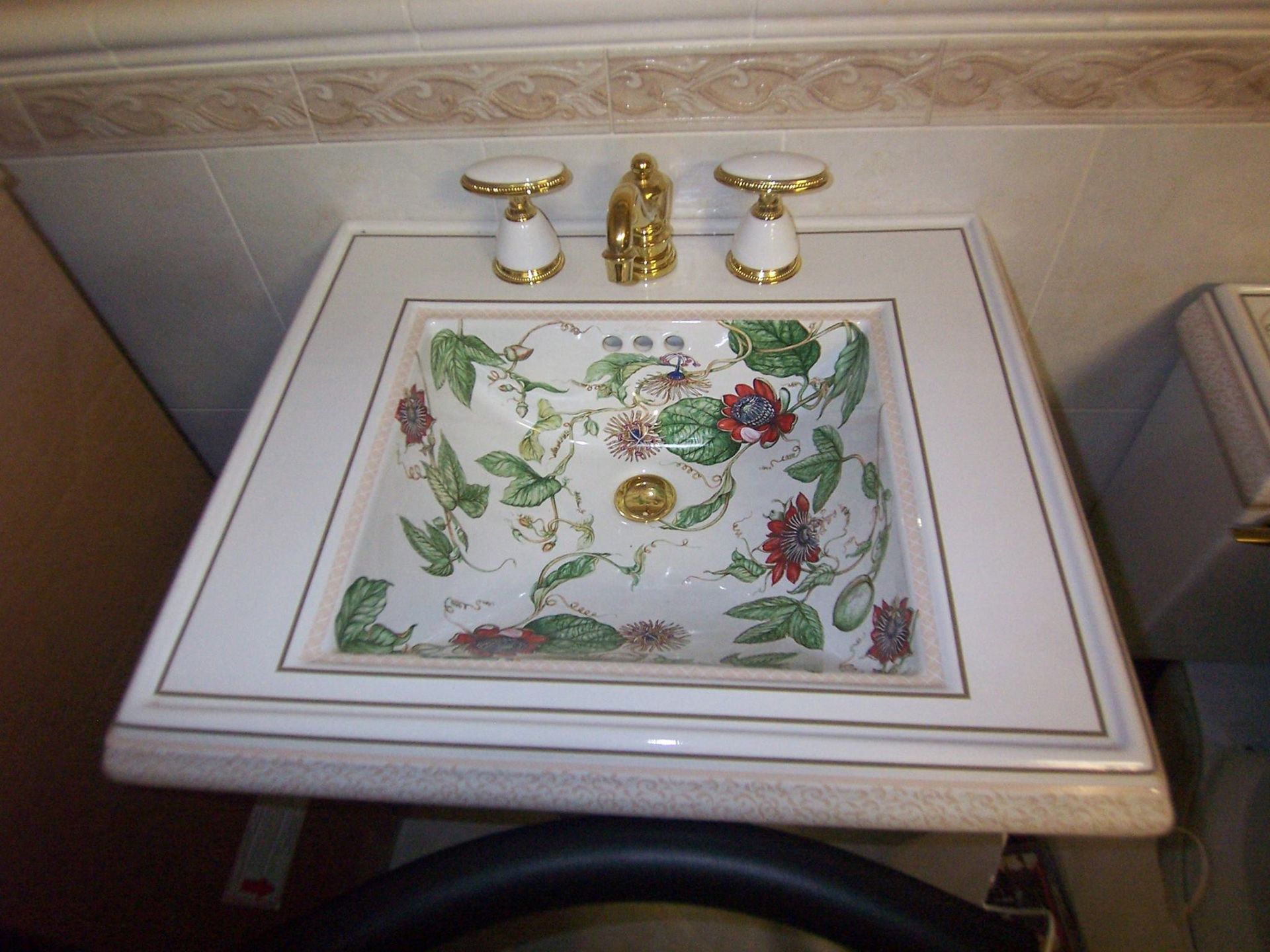 Floral patterned bathroom sink with gold fixtures.