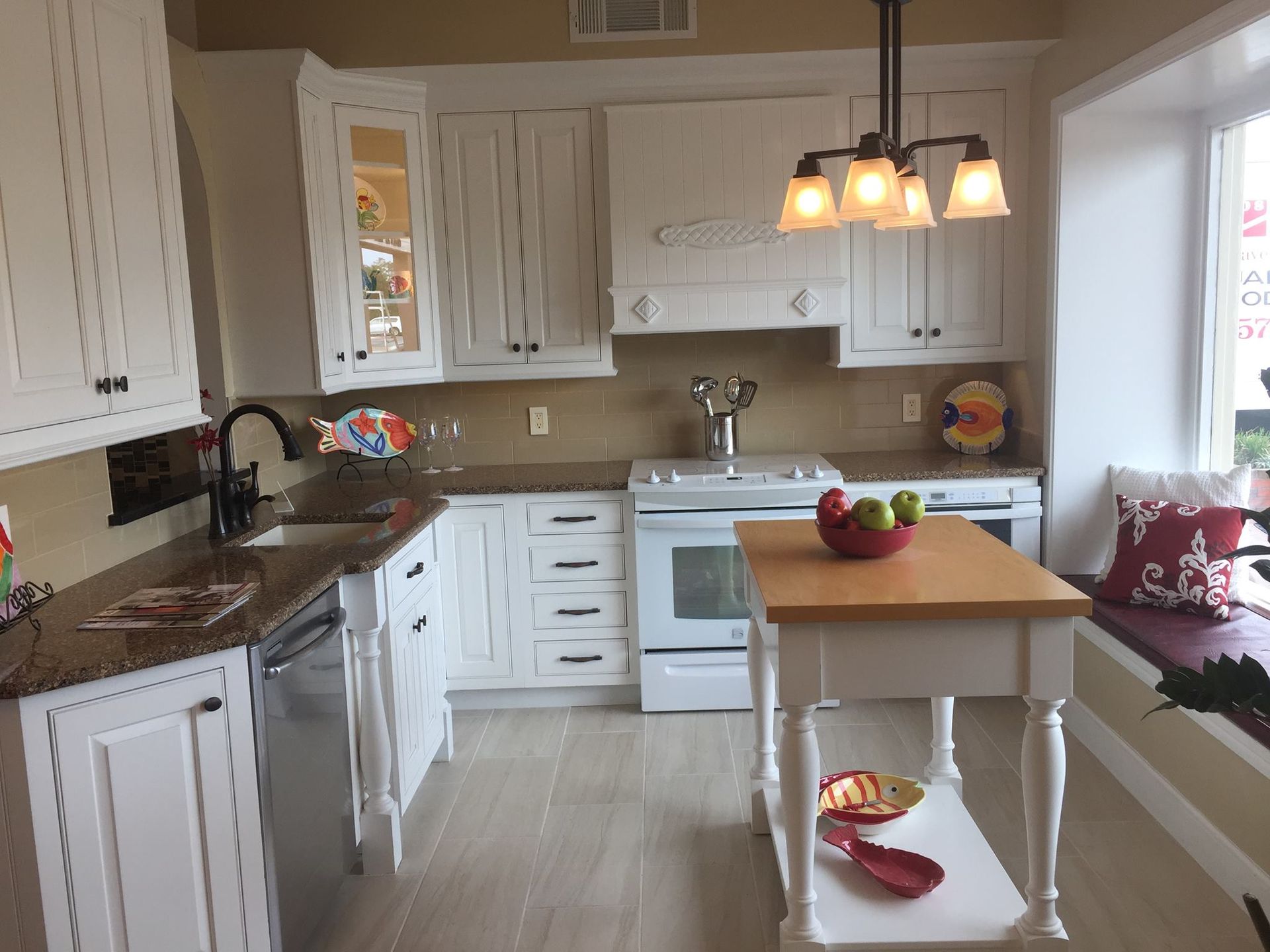 White kitchen with island, cabinets, oven, and window seat.