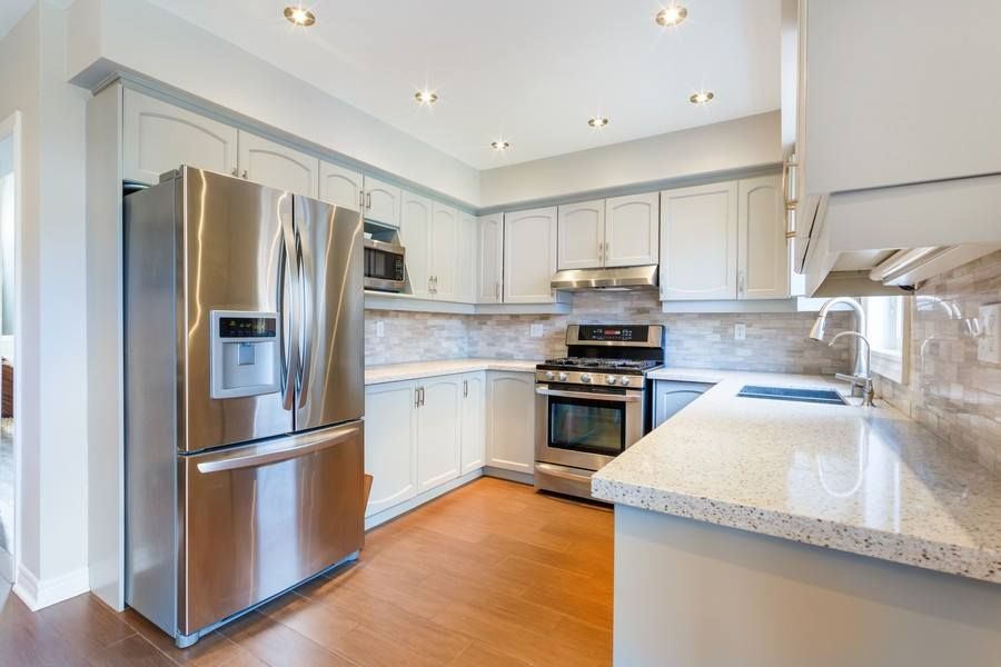 Modern kitchen with stainless steel appliances, light cabinets, and granite countertops.