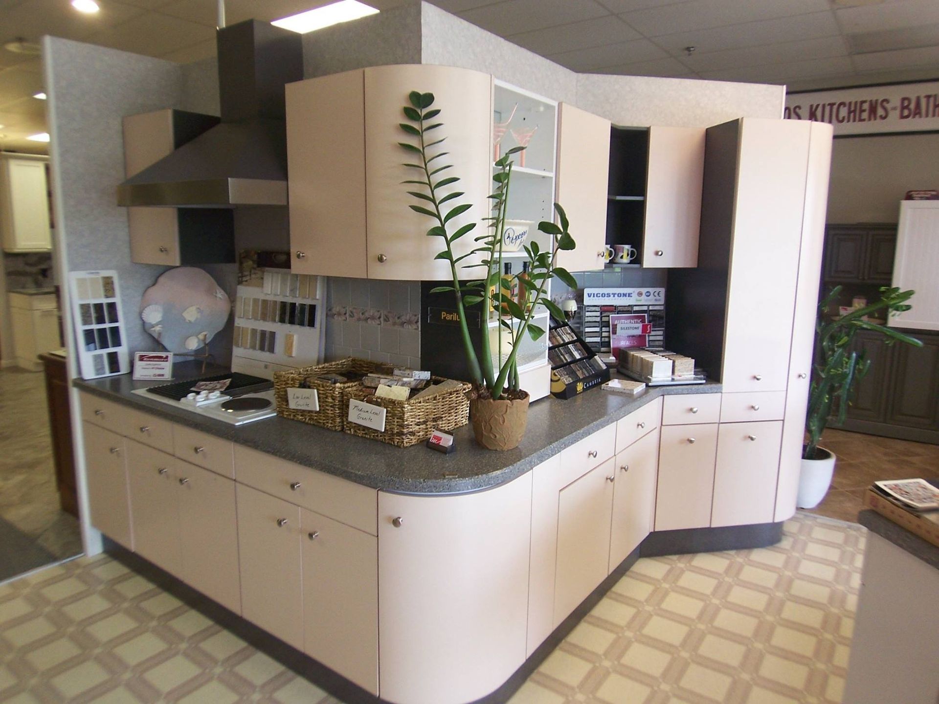Kitchen display with light pink cabinets, gray countertop, and patterned floor.