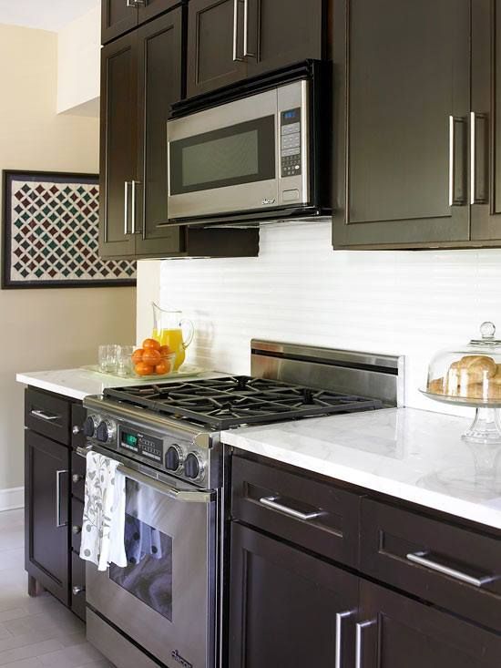 Modern kitchen with dark brown cabinets, white countertops, and stainless steel appliances.