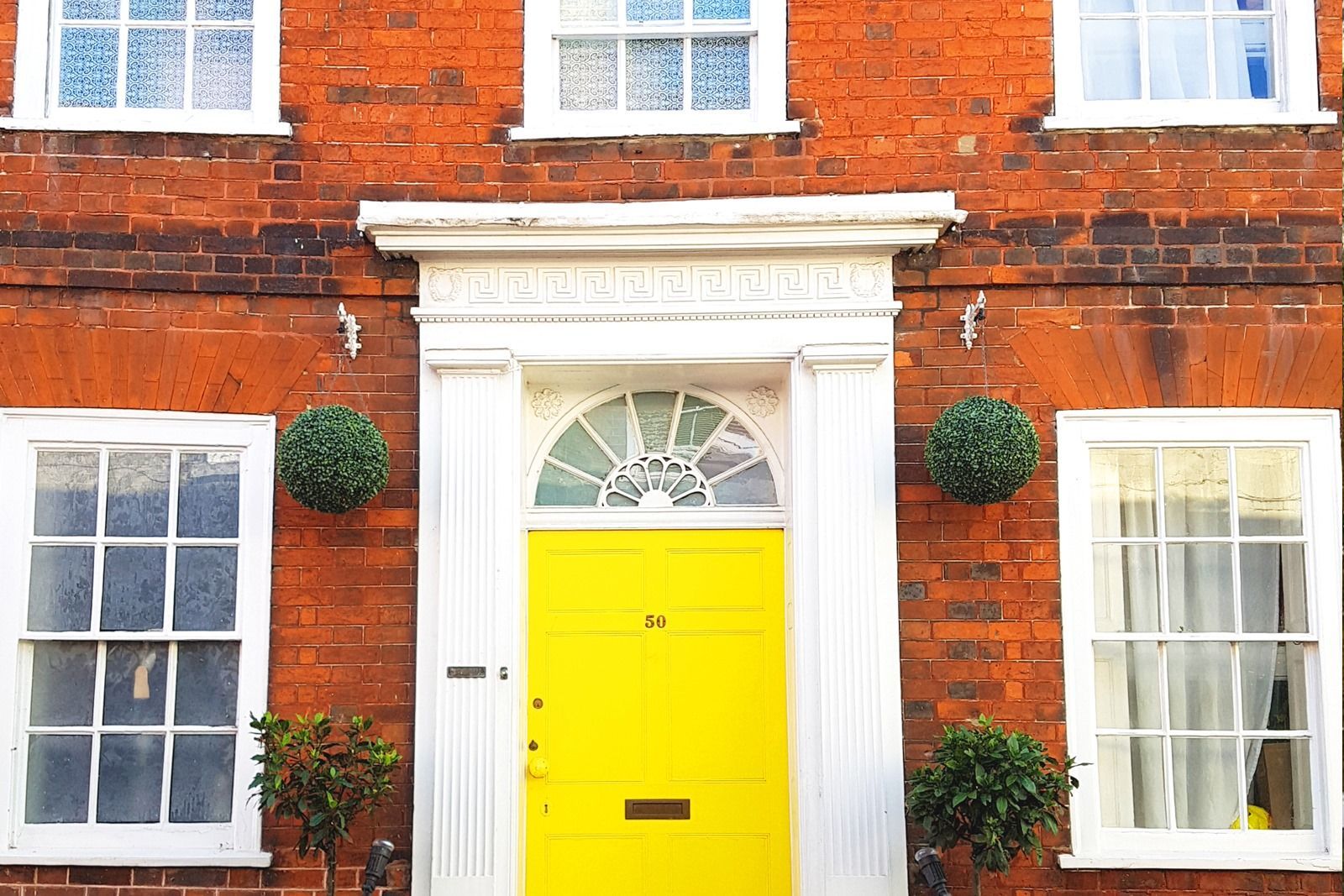 Red brick house with bright yellow door and white trim.