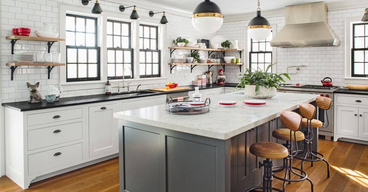 Kitchen with white brick walls, island with seating, and open shelving.