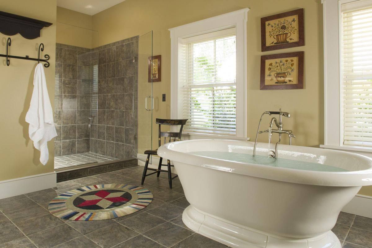 Bathroom with a white clawfoot tub, glass shower, and beige walls.