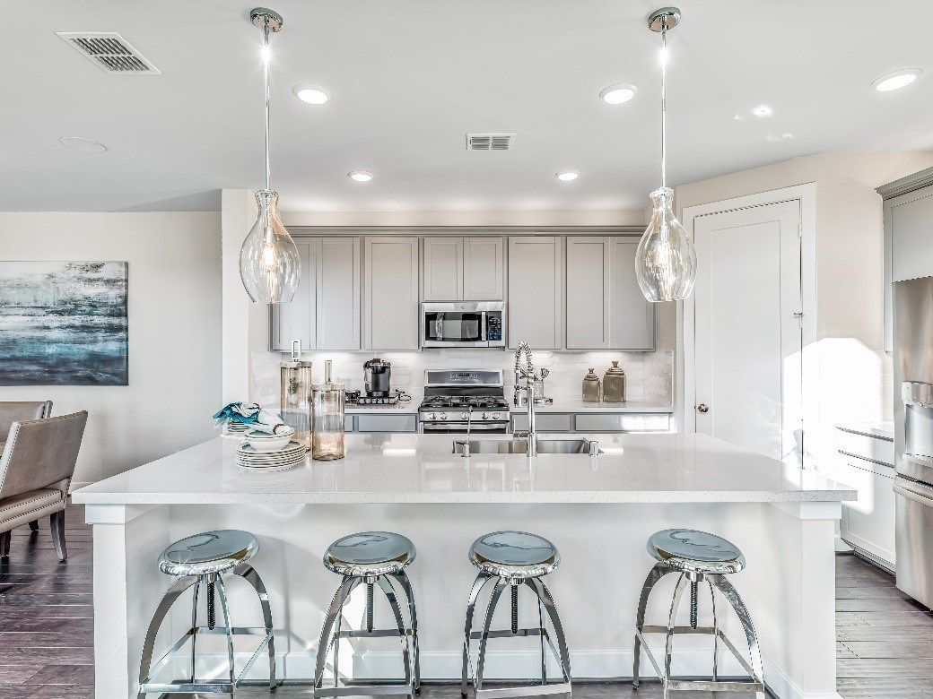 Modern kitchen with white cabinets, island with stools, and pendant lights.