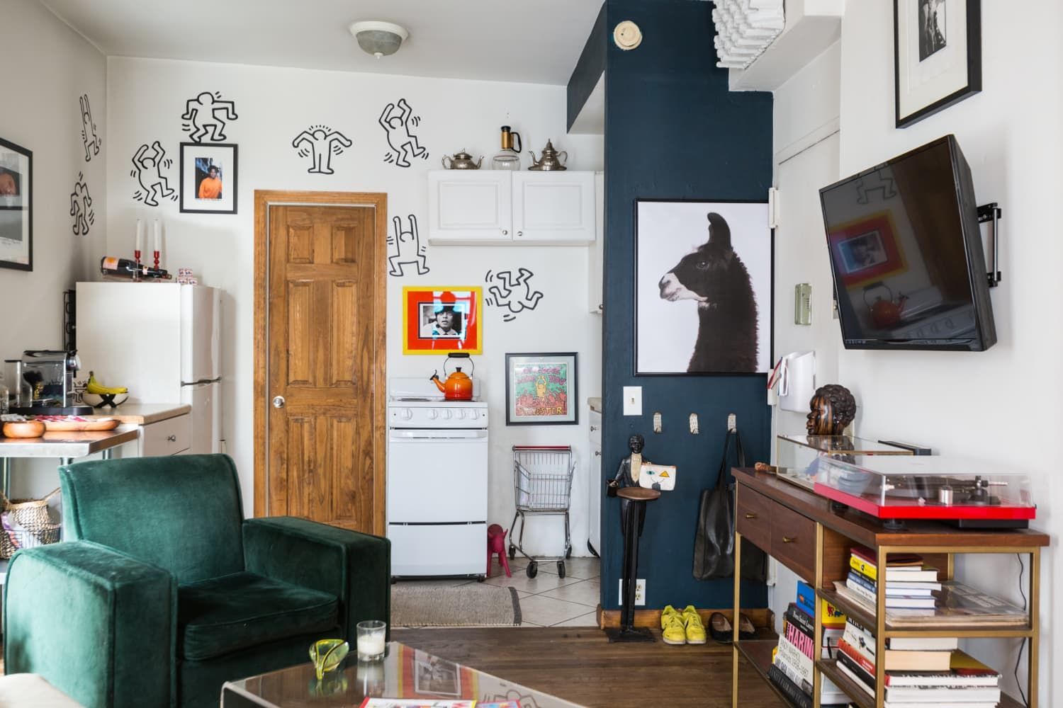 Cozy apartment interior with a green armchair, artwork, and a record player.