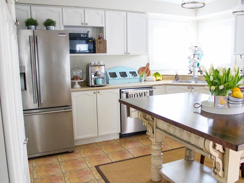 White kitchen with stainless steel appliances, a center island, and tiled floor.