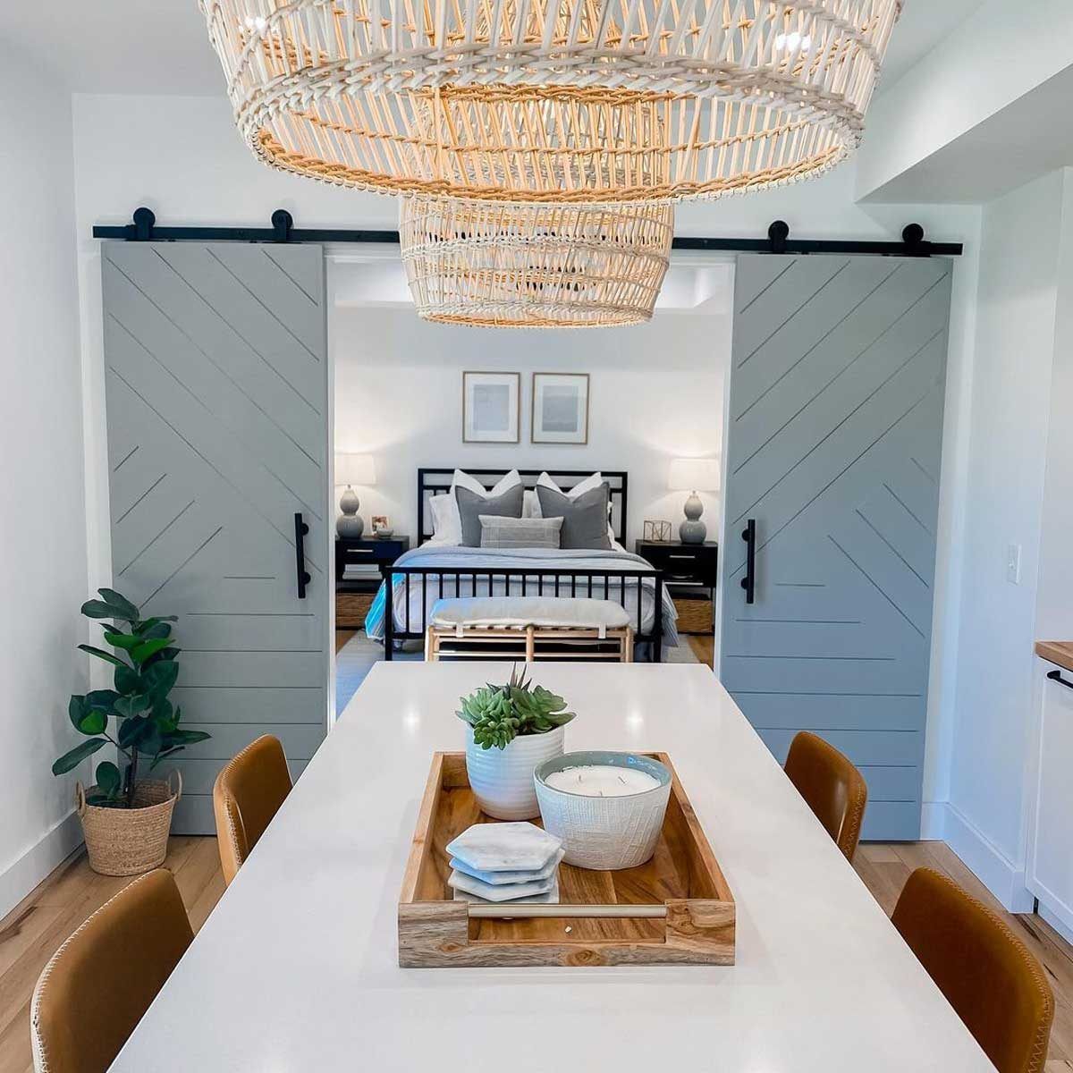 Dining room with white table, sliding gray barn doors leading to a bedroom.