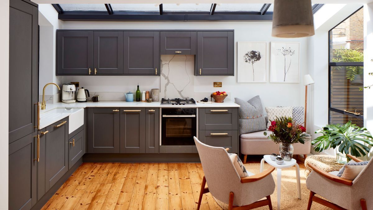 Gray kitchen with wood floor, white counter, cabinets, oven, and seating area.