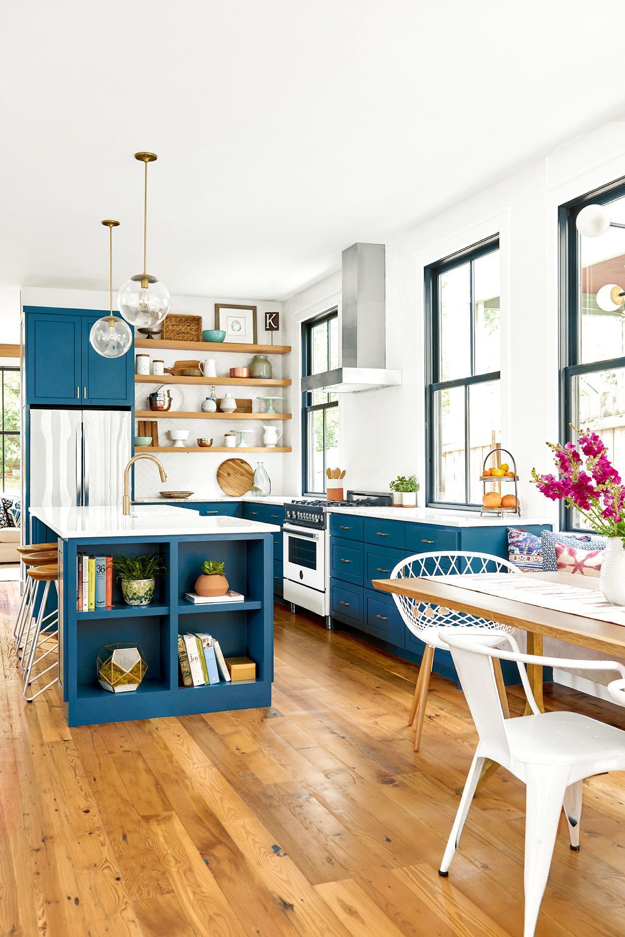 Blue kitchen with wood floors, white countertops, and open shelving.