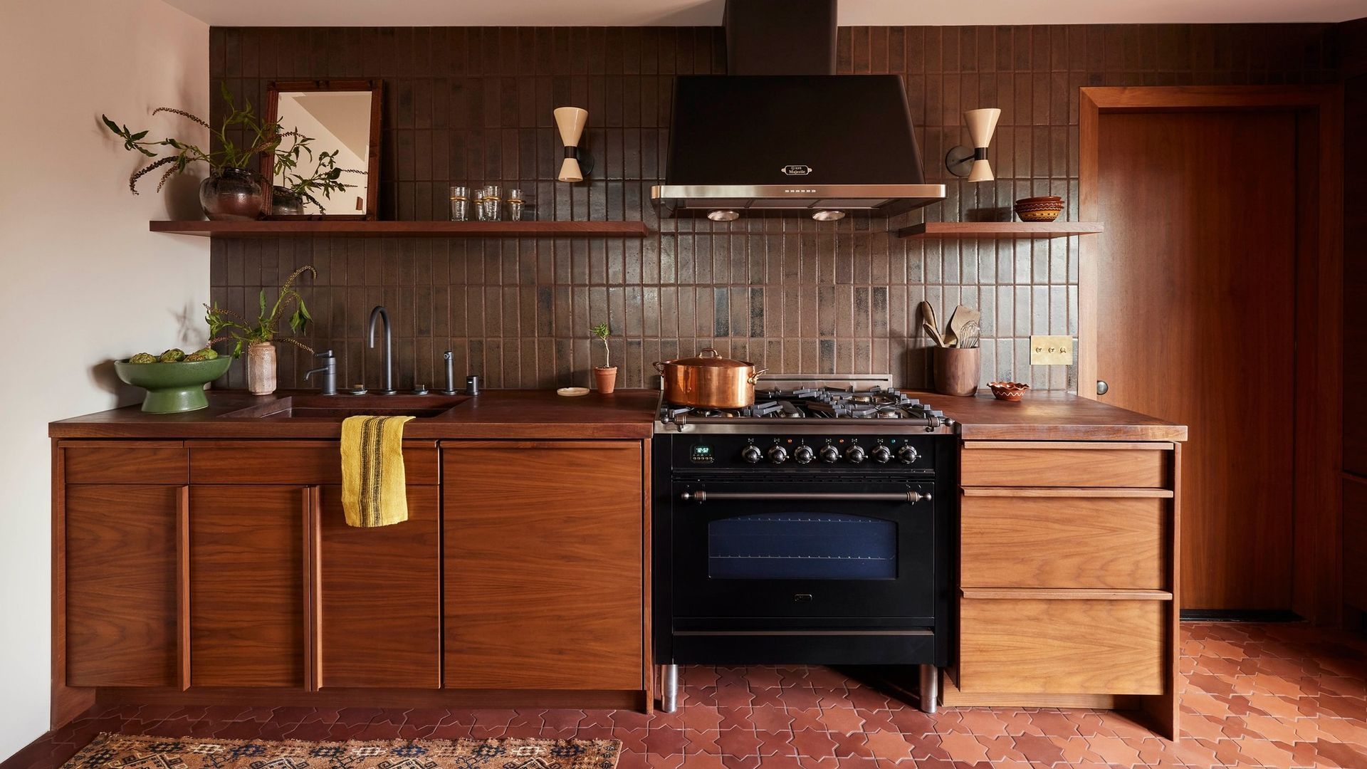 Mid-century modern kitchen with wood cabinets, black oven, and copper-colored accents.