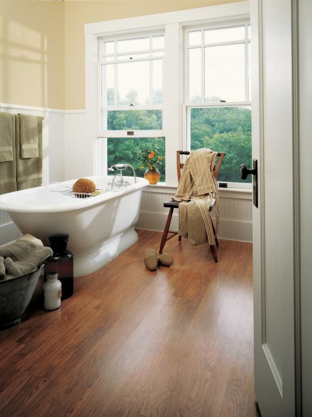 Bathroom with hardwood floors, clawfoot tub, two windows, and wooden chair with clothing.