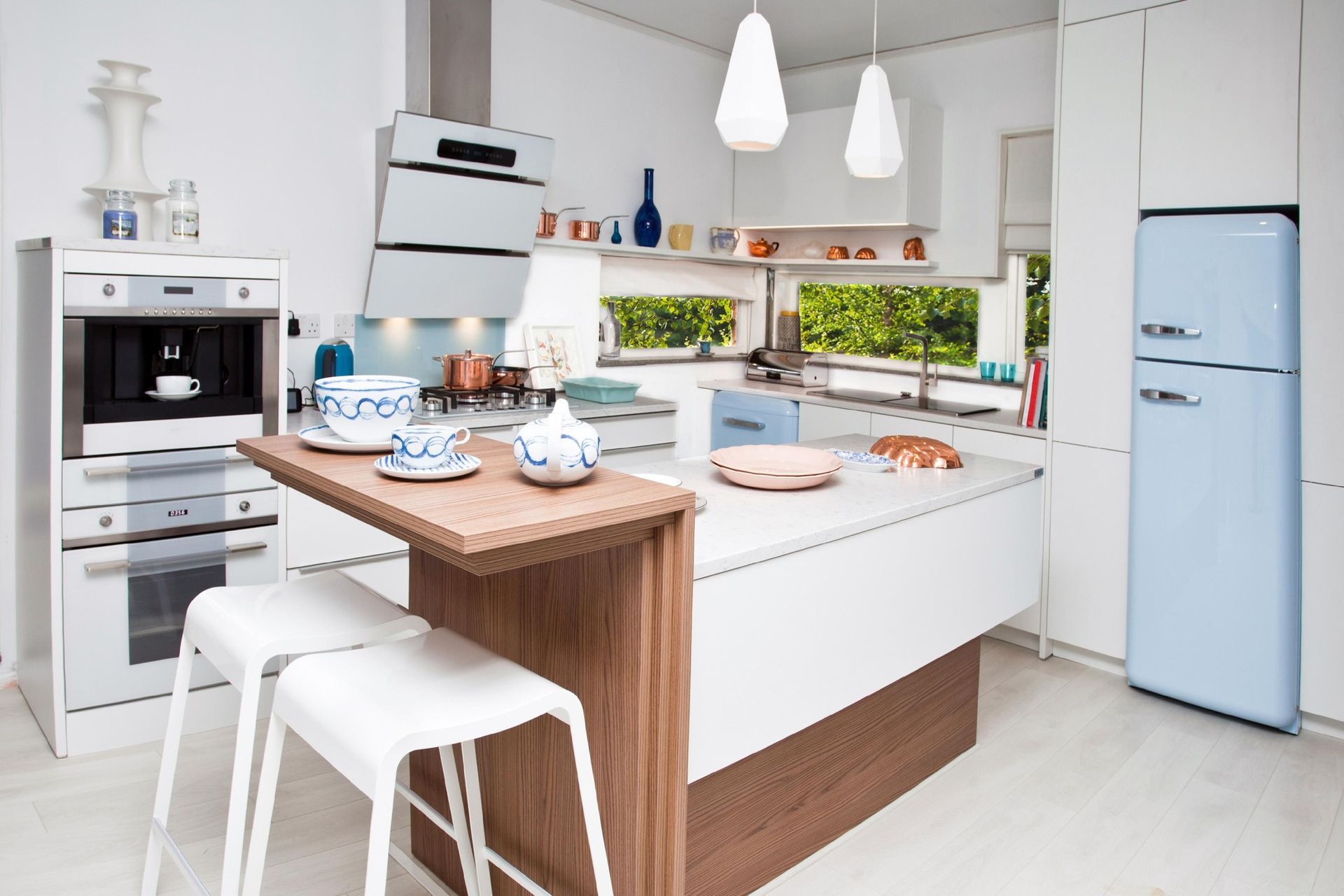 Modern kitchen with white cabinets, light blue refrigerator, and breakfast bar with stools.
