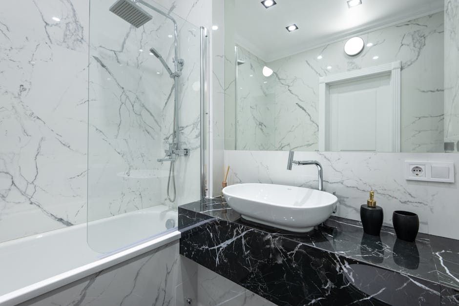 Modern bathroom with white marble walls, black marble countertop, and a white oval sink.