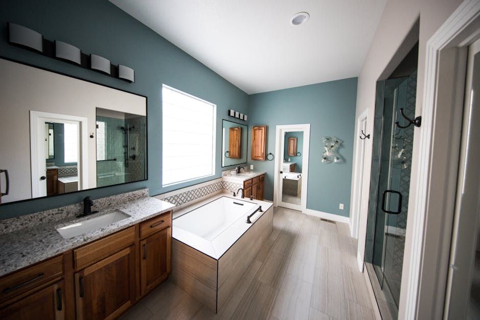 Spacious bathroom with a bathtub, dual sinks, and a walk-in shower; teal walls, wood cabinets, and light floors.
