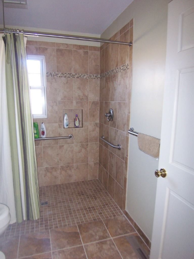Accessible bathroom with tile shower, grab bars, and a shower curtain.