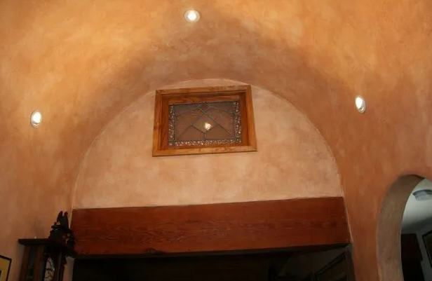 Arched, orange-toned ceiling with embedded lights and a framed window. A dark wooden beam runs below.