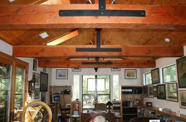 Interior with exposed wooden beams, black metal supports, and art-filled walls.