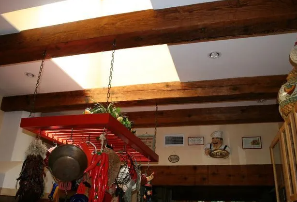 Wooden beams on a white ceiling with a red pot rack hanging below.