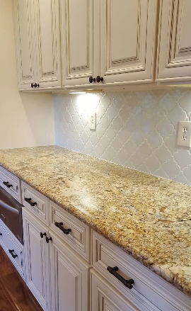 Kitchen cabinets with granite countertop and a tiled backsplash.