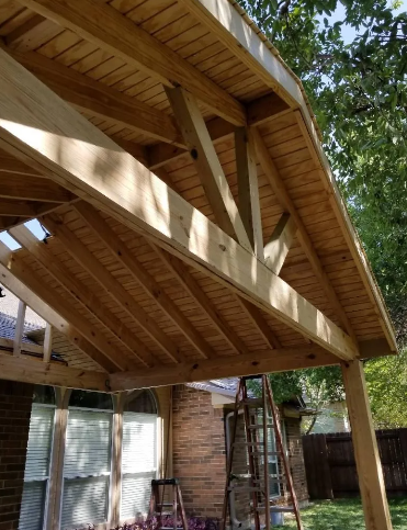 Wooden patio roof construction with supporting beams and rafters.