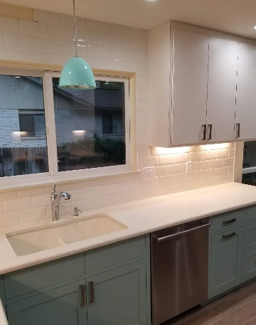 Modern kitchen with blue and white cabinets, white countertops, stainless steel appliances, and a turquoise pendant light.